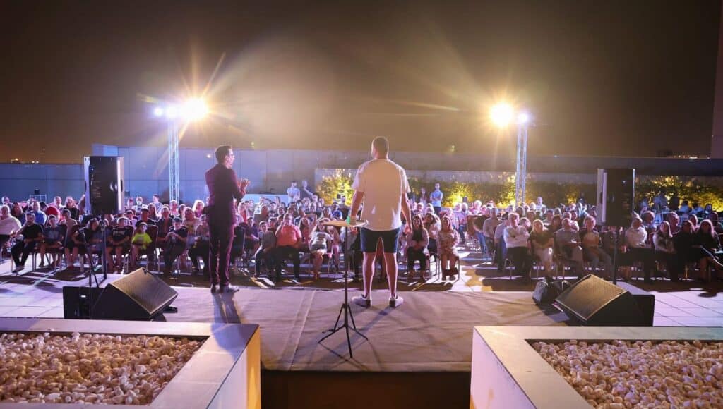 הופעה חיה - שני אמנים על במה בפני קהל גדול בחוץ בלילה